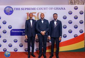 Dr Nana Yaw Sapong standing in front of the Supreme Court of Ghana's 150th anniversary banner